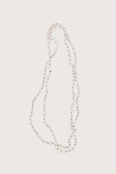 flat lay Veil Pearl Necklace Irregular shaped pearls
Threaded and knotted onto a contrasting black silk
Can be worn doubled around the neck, crossed over the body as a sash from the sea, or crafted into a belt to provide luster and accent to layered fabric
Baroque pearls and black silk
Necklace measures 1.2 meters in length