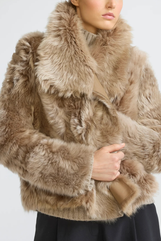 front profile model wearing  fur side Veste Reversible Fur Jacket Chai Latte beige Unlined Toscana lambskin
Two piped pockets
Front hook-and-eye fastening
Draped collar
Long-haired lamb
Wide cut
100% Lamb