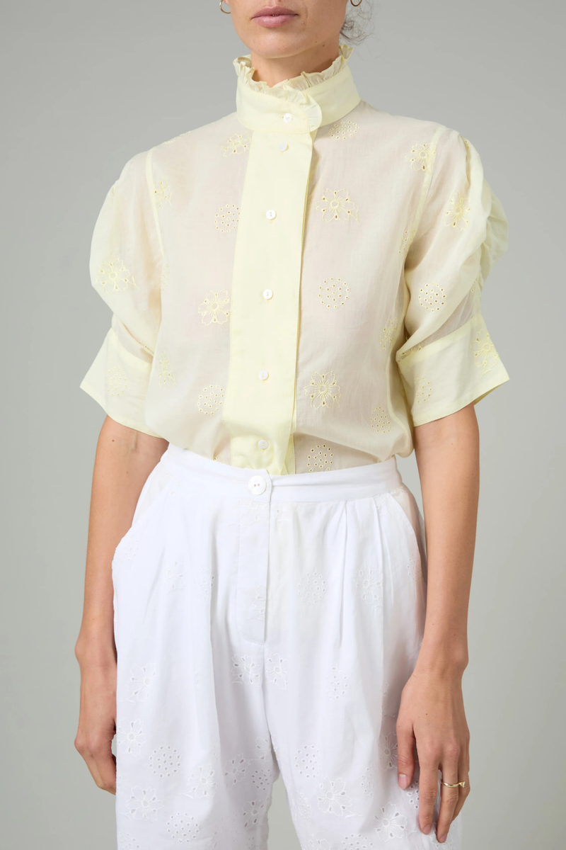 front profile model wearing Vita Embroidered Voile Short Sleeve Top yellow Embroidery throughout
Puff sleeves
Ruched sleeves with thick cuffs
High collar with ruffles
Button front

Side slit
100% Cotton