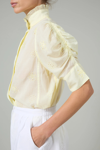 side profile Vita Embroidered Voile Short Sleeve Top yellow Embroidery throughout
Puff sleeves
Ruched sleeves with thick cuffs
High collar with ruffles
Button front

Side slit
100% Cotton