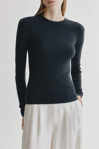 front profile model wearing  Vivian Long Sleeve Ribbed T-Shirt Navy Knitted long-sleeve T-shirt
Fine single rib knit cashmere blended with cotton
Fitted, hip-length silhouette
Round neck
Full-length sleeves
Straight hem
70% Cotton, 30% Cashmere