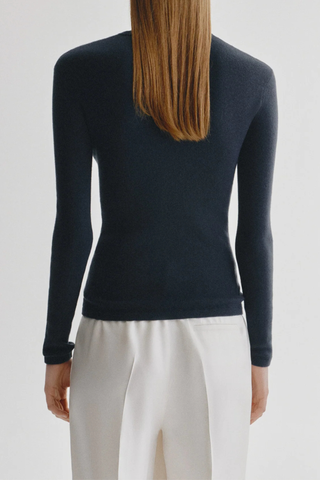 back profile model wearing  Vivian Long Sleeve Ribbed T-Shirt Navy Knitted long-sleeve T-shirt
Fine single rib knit cashmere blended with cotton
Fitted, hip-length silhouette
Round neck
Full-length sleeves
Straight hem
70% Cotton, 30% Cashmere