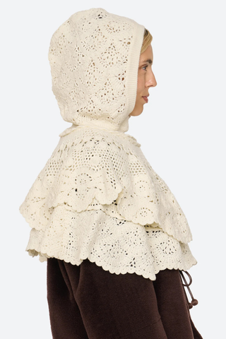 side profile model wearing with hood on Wright Poncho cream Knit poncho
Hand crocheted
Tiered layers of intricate crochet
Create a dimensional, textural silhouette
Finished with a hood
100% wool

Slip on
Relaxed fit