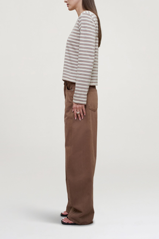 side profile model wearing Wynn Long Sleeve Stripe T- Shirt Apricot Stripe 
Relaxed boxy fit
Subtle cropped length
Roomy sleeves
Slight taper at waist
Shifted side seams give a tailored look
Solid binding at neckline
Subtle tonal logo embroidery at hip
100% Cotton