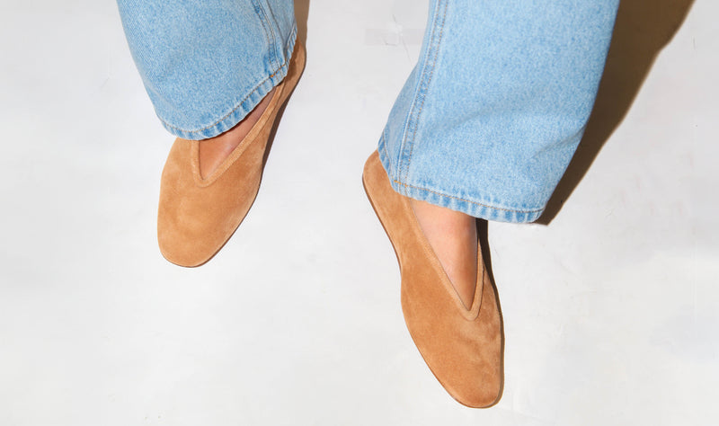 model wearing camel color suede flats from le monde beryl with bottom part of light blue jeans showing. 